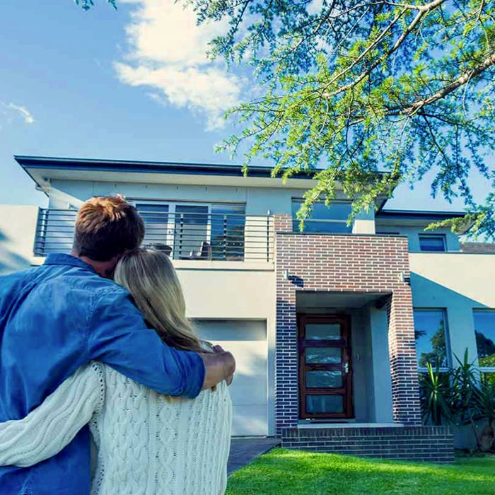 couple-standing-in-front-of-modern-home